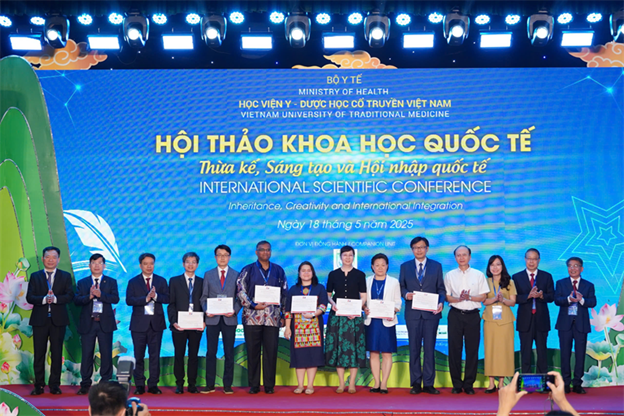 A group of people standing on a stage holding certificates

Description automatically generated